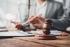 Gavel with two legal professionals behind